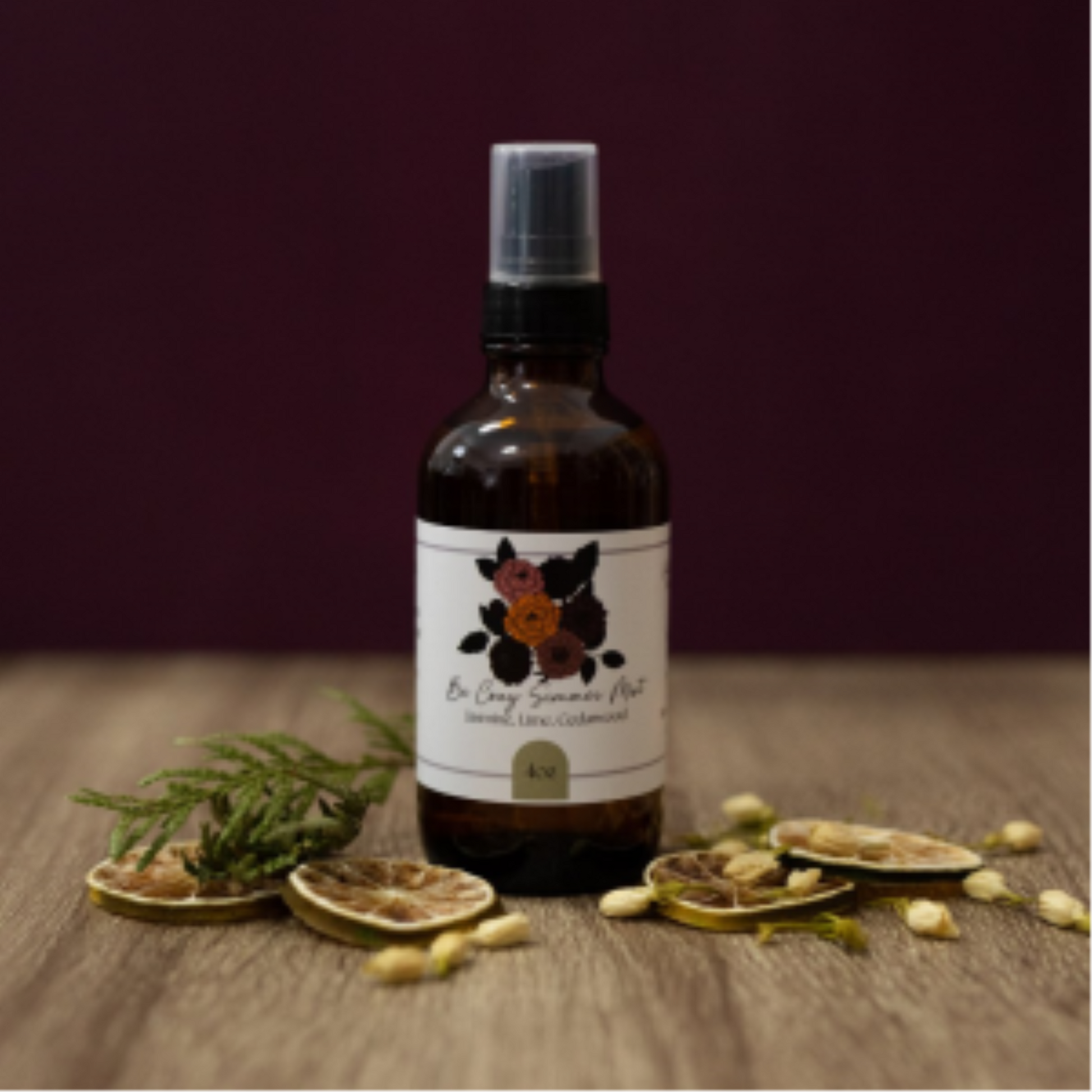 A bottle of Be Cozy Simmer Mist fragrance spray on a wooden surface with citrus slices and cedar.